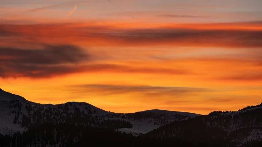 a sunset with a plane flying in the sky