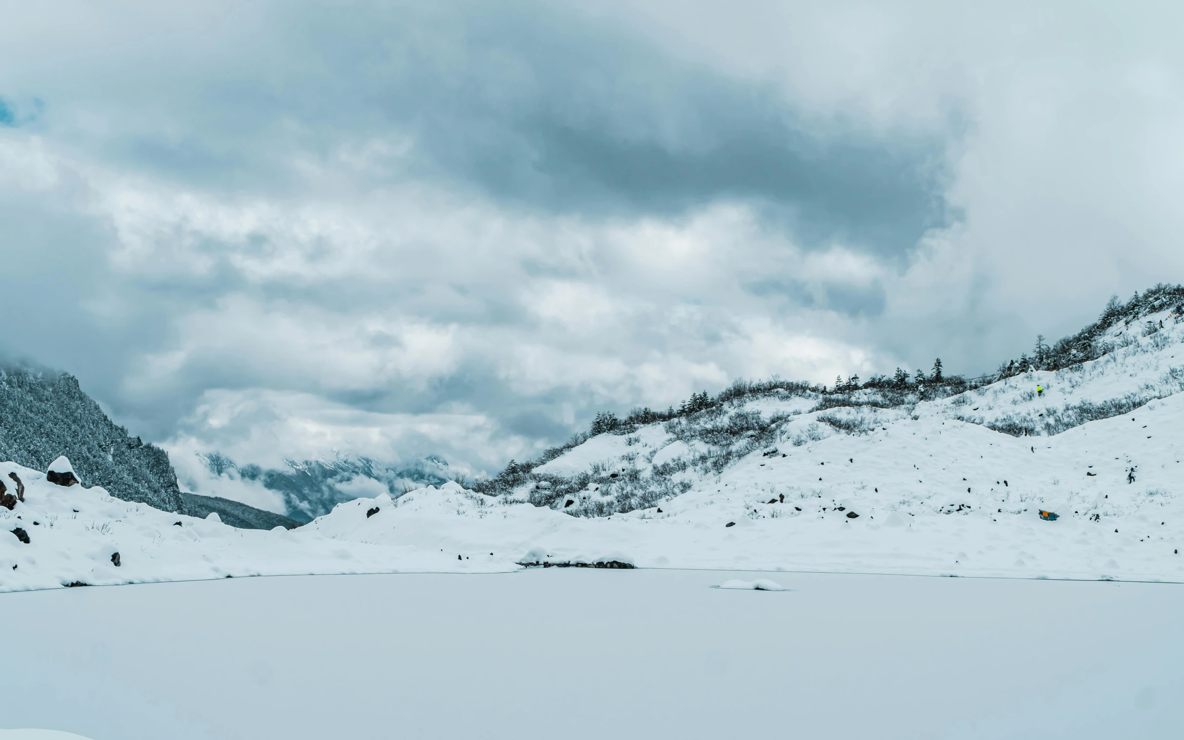 the clouds are above mountains covered with snow