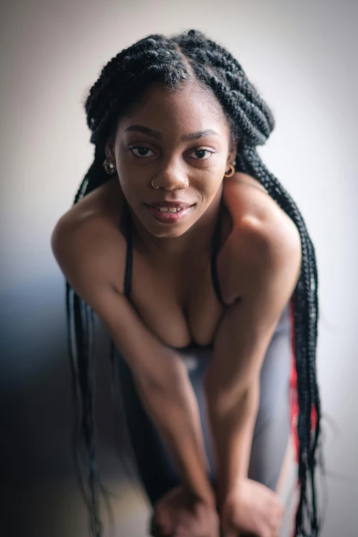 a black woman sitting down in front of a white wall