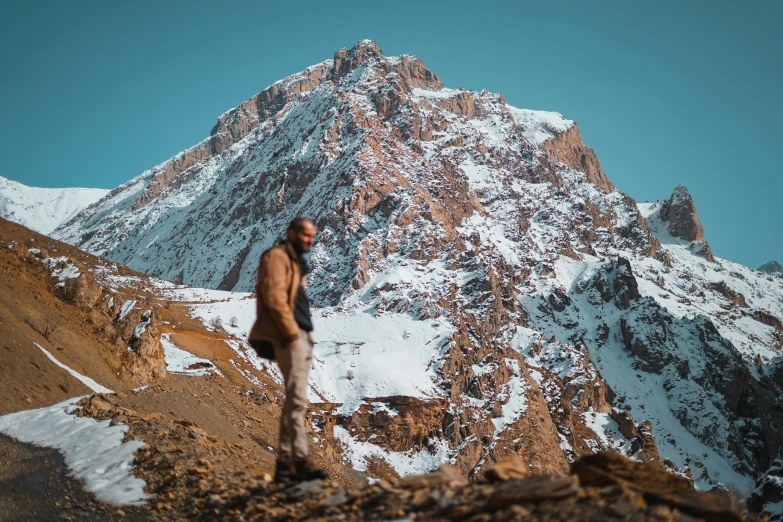 a person standing on a mountain with a large snow covered mountain behind them