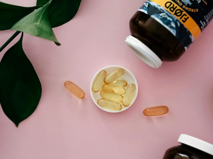 vitamins and tablets sitting on top of a pink surface