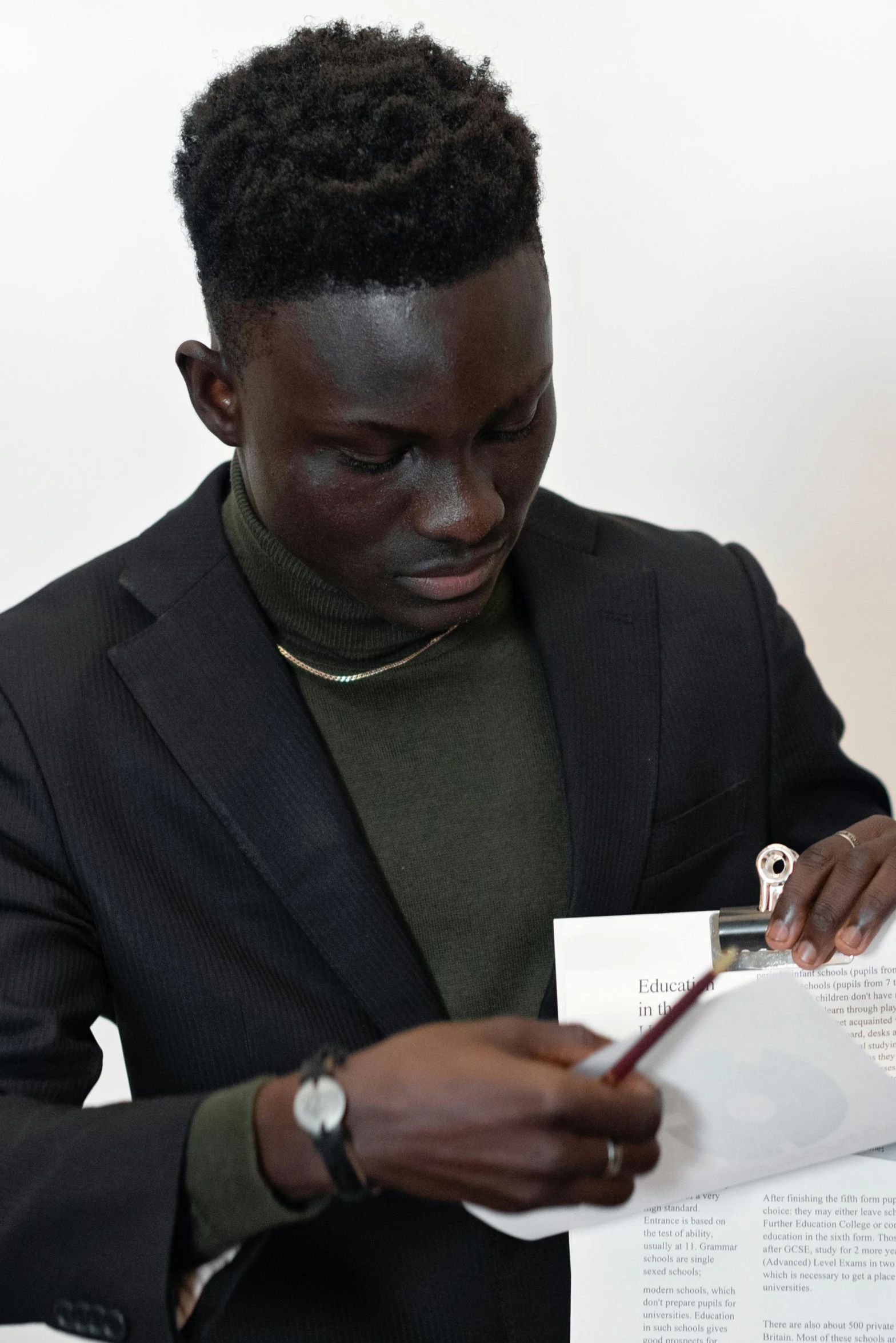 a black man holding a piece of paper in his left hand and writing on it with a pen