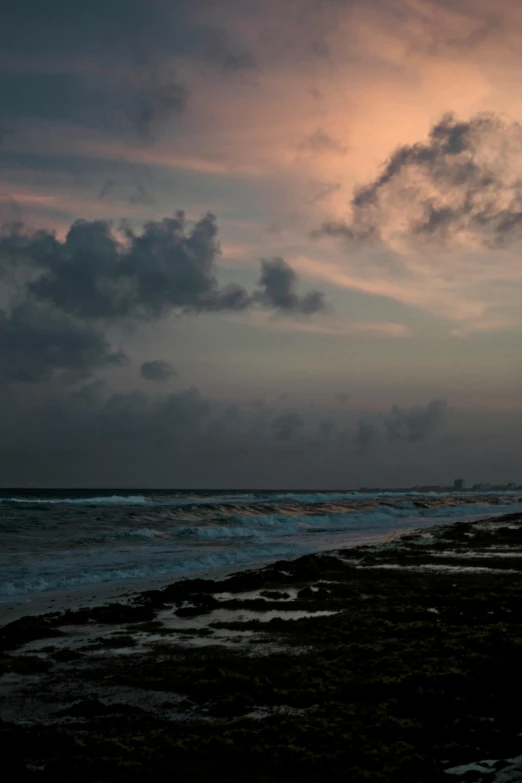 two men standing on the shore of a beach during sunset