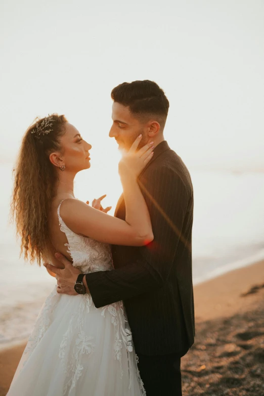 the bride and groom are posing at sunset by the water