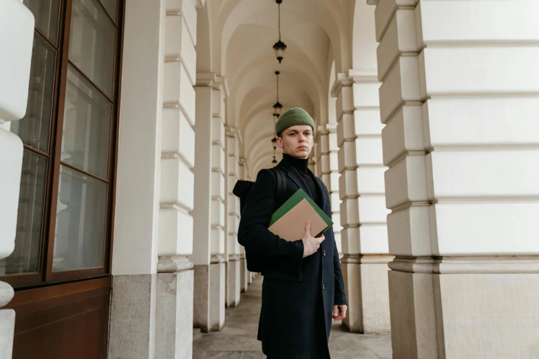 a man standing outside of an entrance to a building with a binder