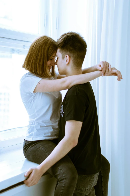 a couple hug while sitting on the windowsill