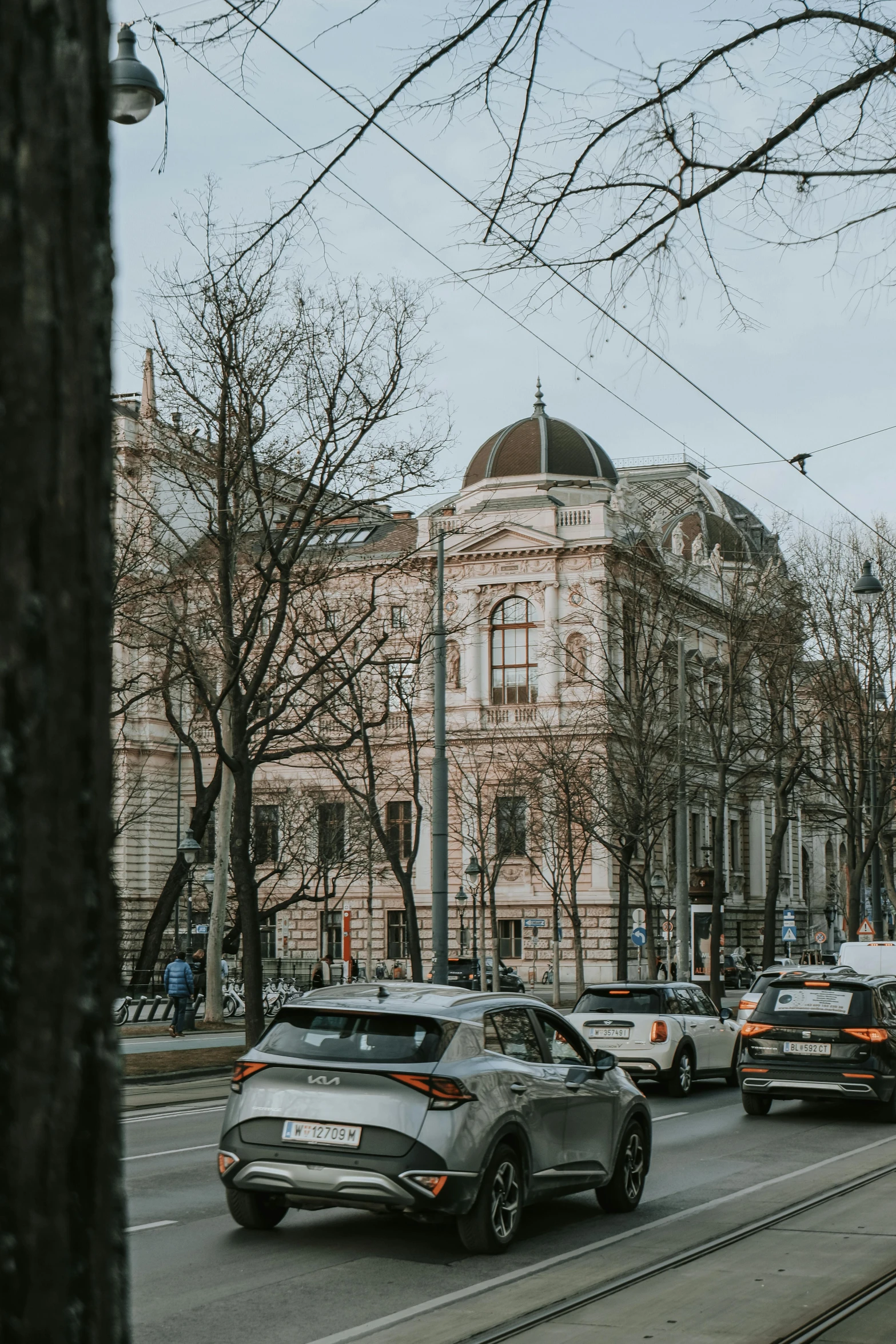 a city street with cars driving by on a cloudy day