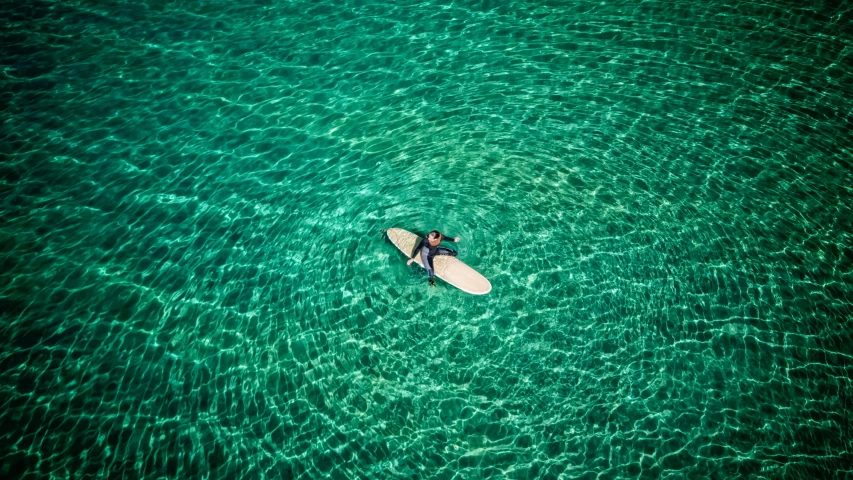 man on a surfboard floating in crystal blue waters