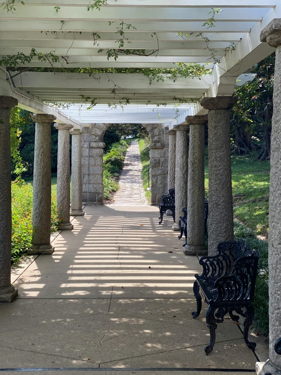 a sidewalk lined with stone columns leading to a park