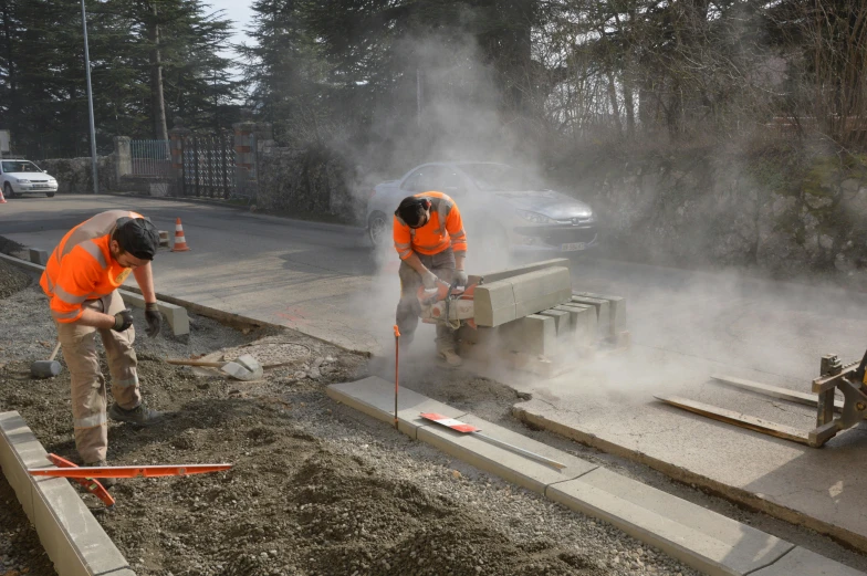 two workers in orange shirts working on concrete