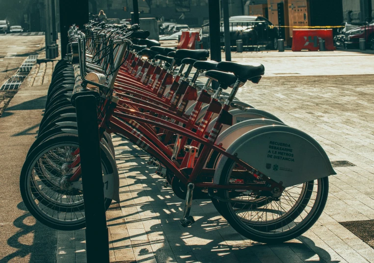 several bikes are parked at a rail on the sidewalk