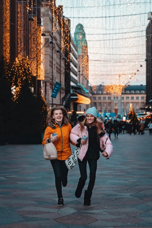 two young women are walking through the city streets