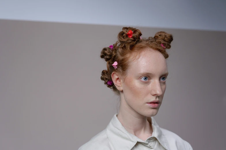 a model with red hair with buns and flowers in her hair