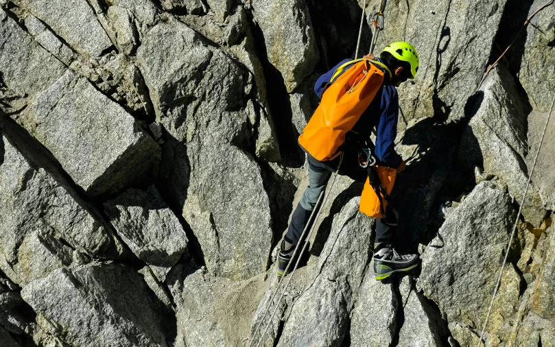 an alpine man is climbing up a steep cliff