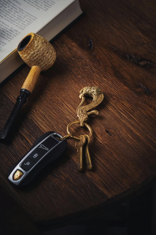 an old style key chain is laying near a book and pen