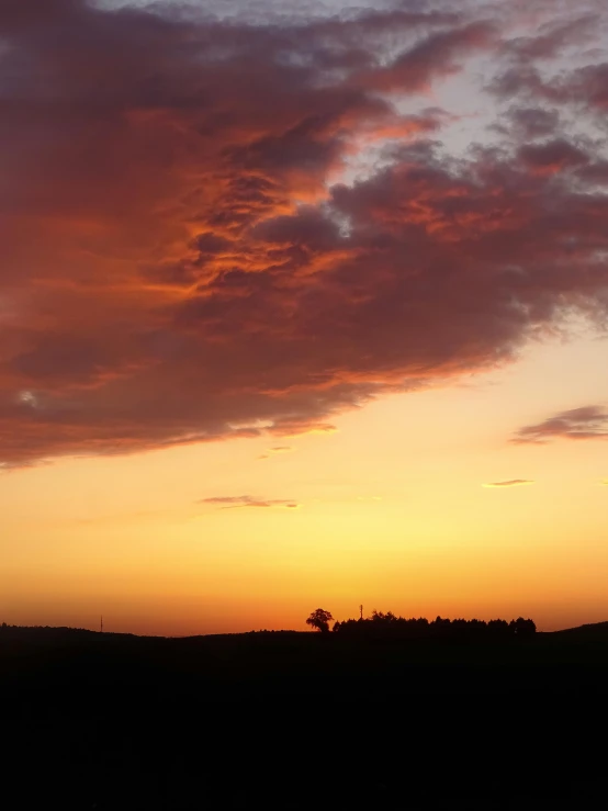 the sun is setting in the sky with dark clouds