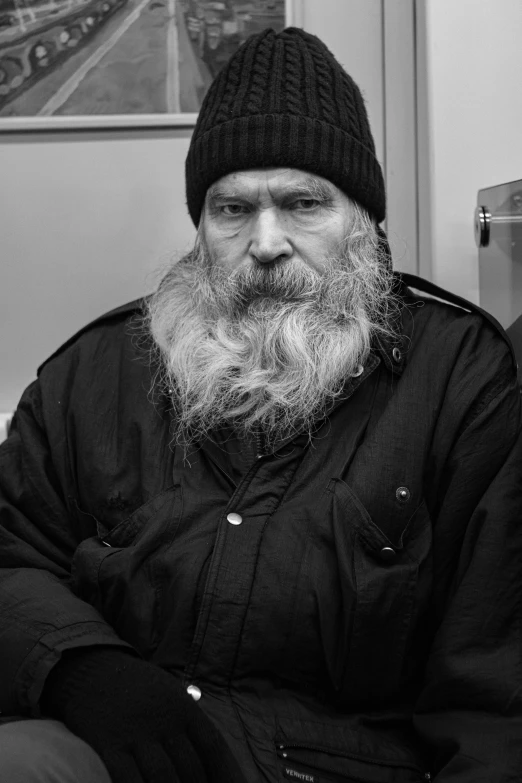 a man in black jacket and hat sitting on chair