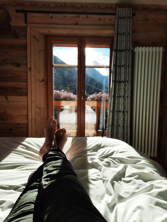 a person laying in bed with their feet propped on the edge