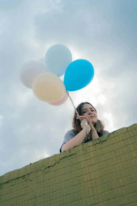 a girl wearing glasses holding several balloons in her hand