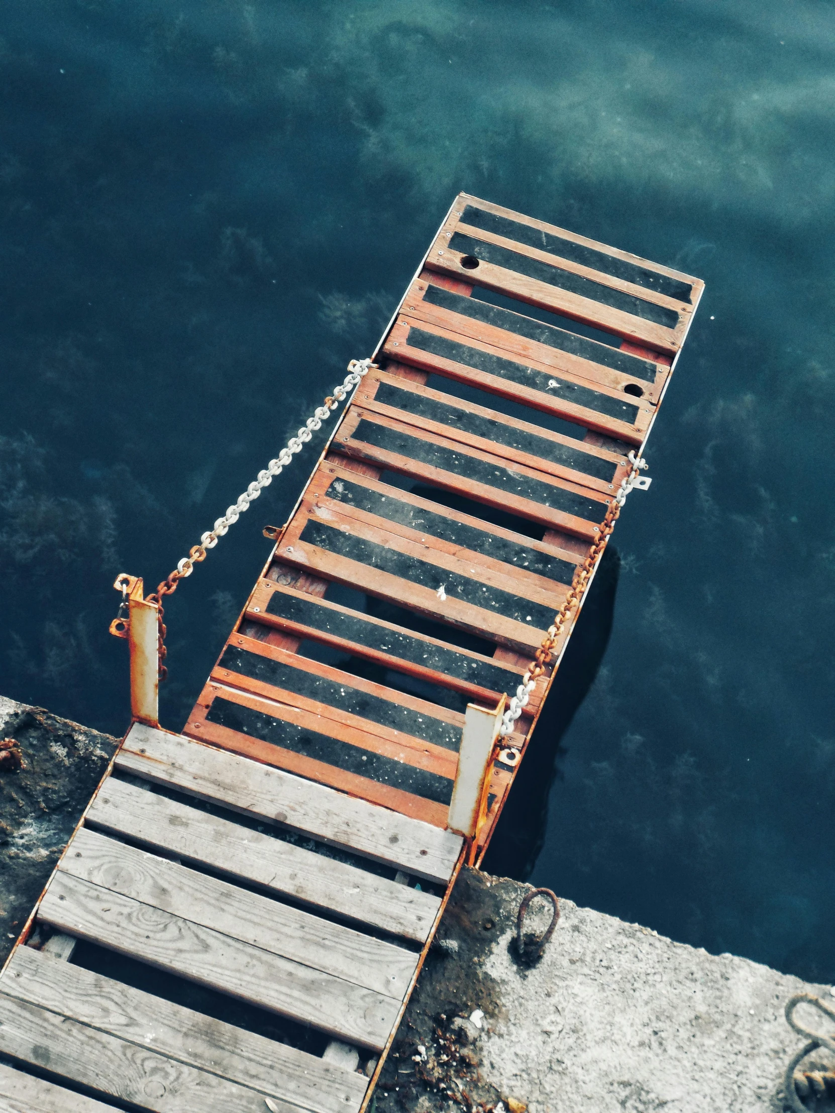 a wooden pier on a body of water with a chain on it