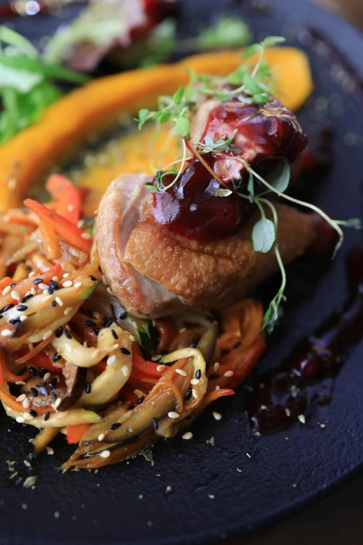 a black plate topped with assorted vegetables and meat