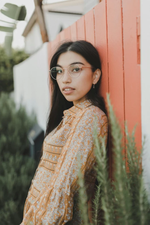 a beautiful young lady leaning against a red building