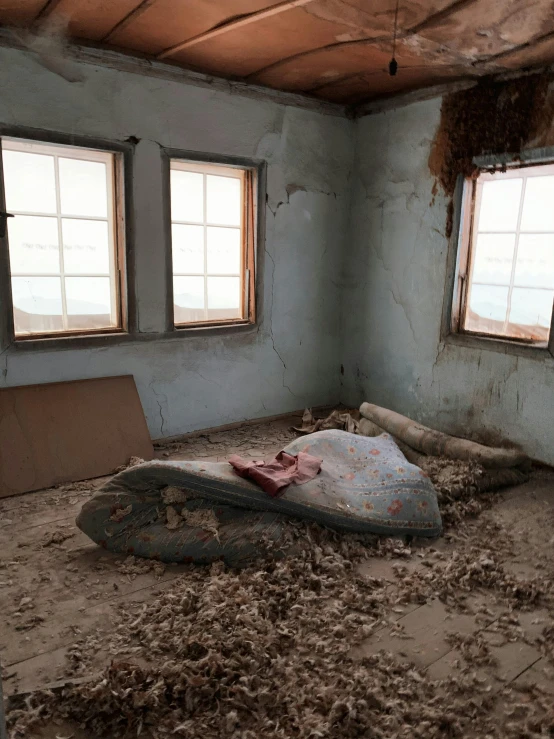 an old room with a mattress and windows