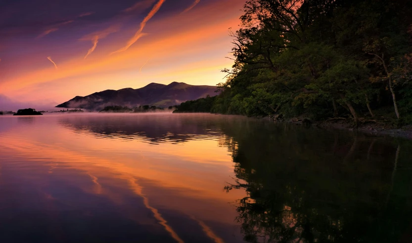 a lake surrounded by mountains with a pink sky