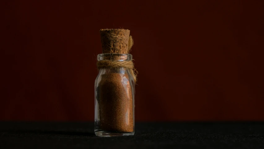 an orange spice in a glass bottle on a black table