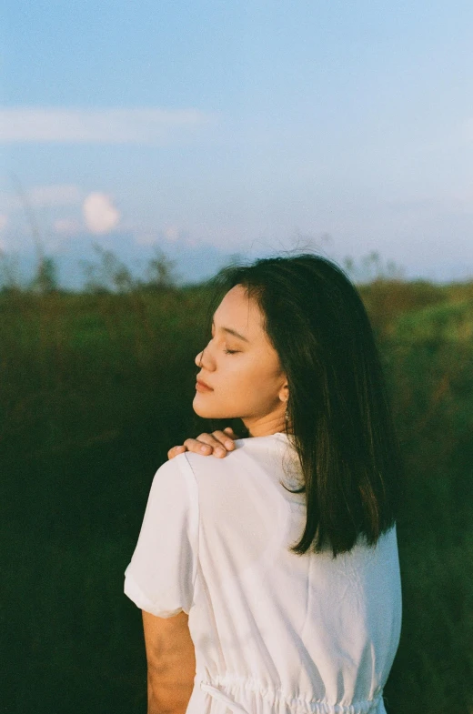 a young woman looks off into the distance with grass in the background