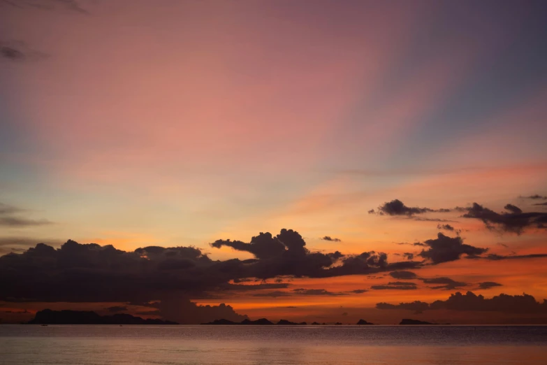 a boat floating out on the ocean at sunset