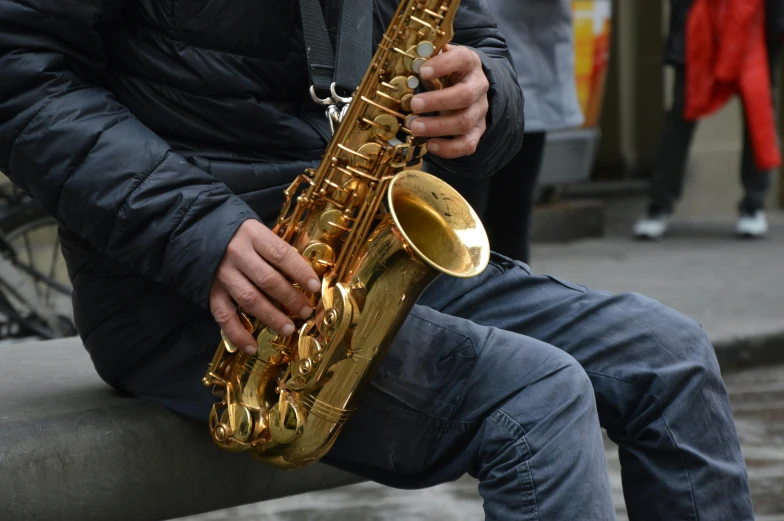 a man in black jacket playing on saxophone