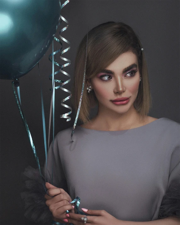 a woman is holding blue balloons and wearing diamond earrings