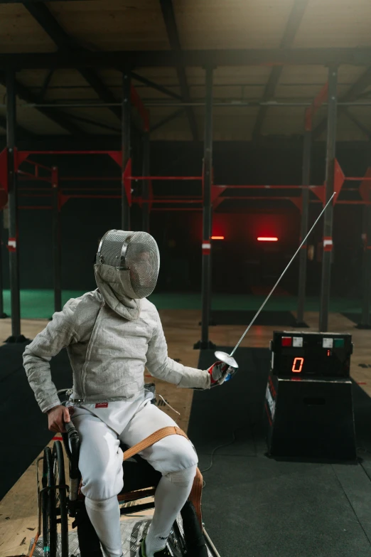 person in white fencing outfit sitting on chair