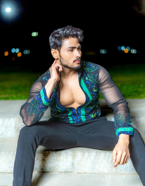 the man is posing on the steps in a colorful shirt