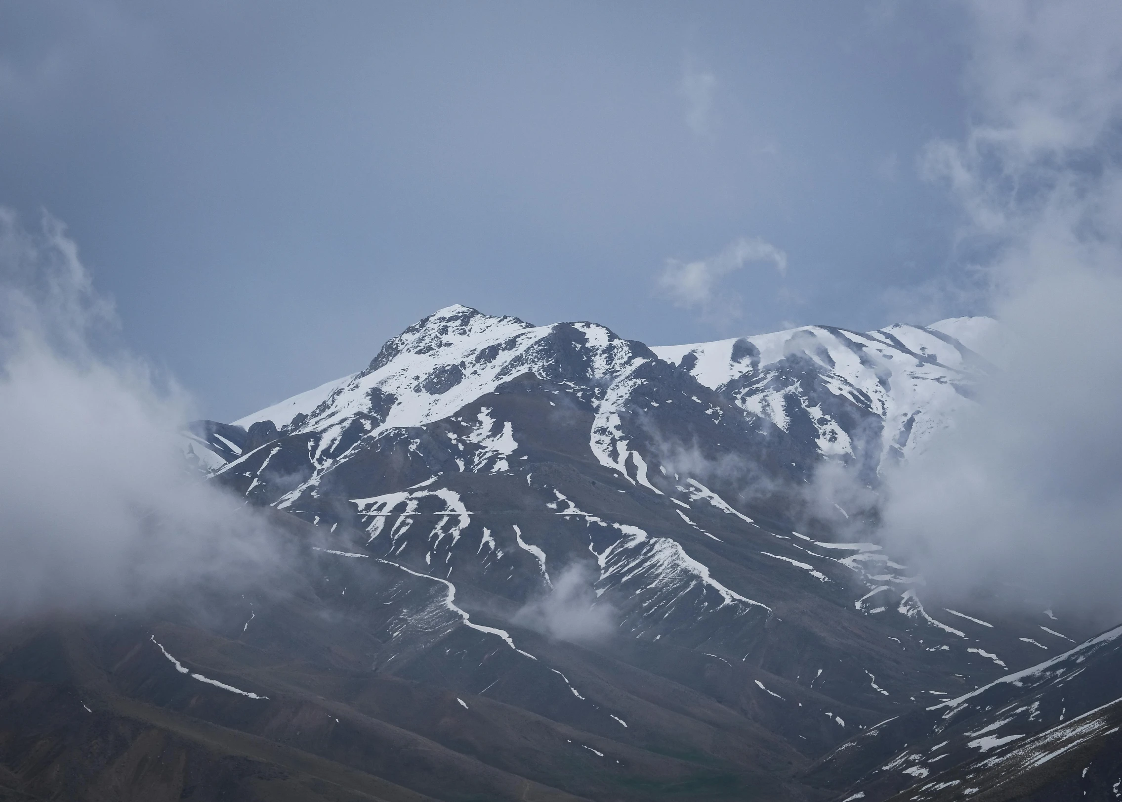 the view of a mountain covered in snow and clouds