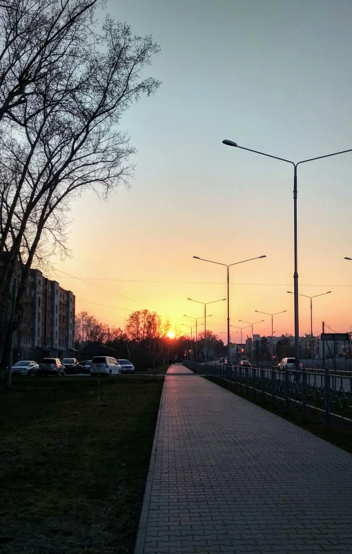 the sun is setting over a street and park