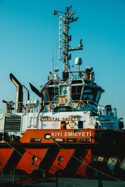 the orange tug boat is parked by itself