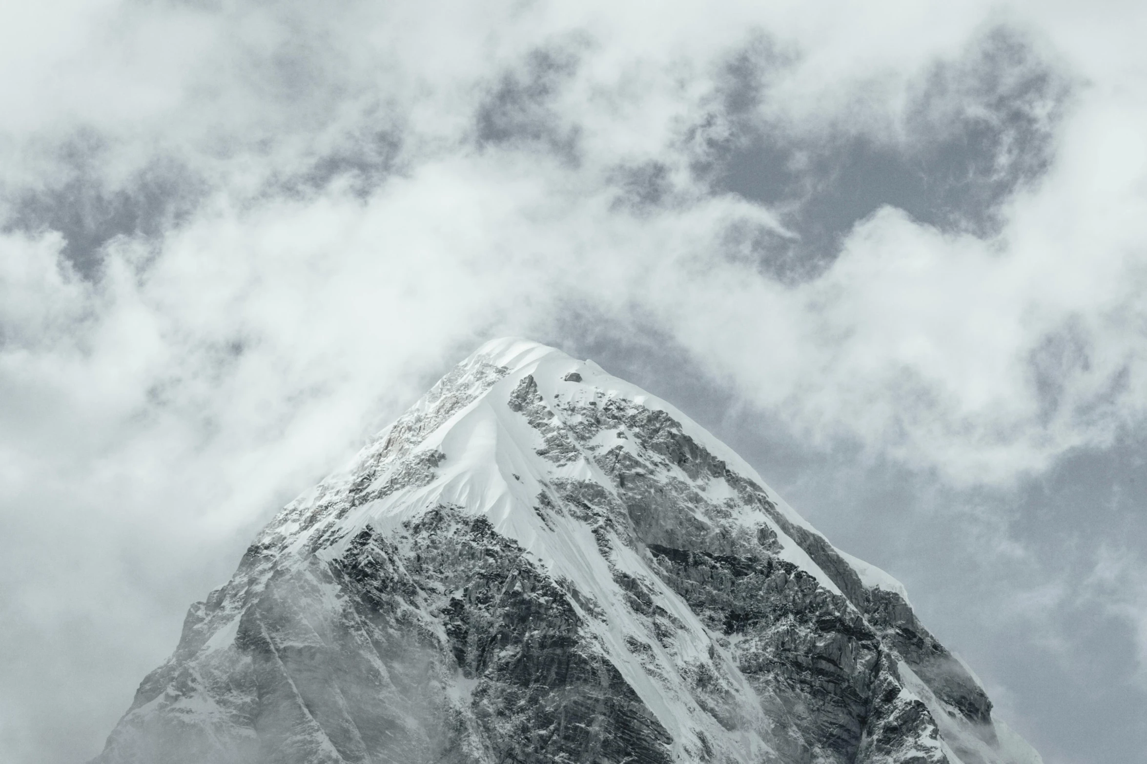 a very tall snow covered mountain in the cloudy sky