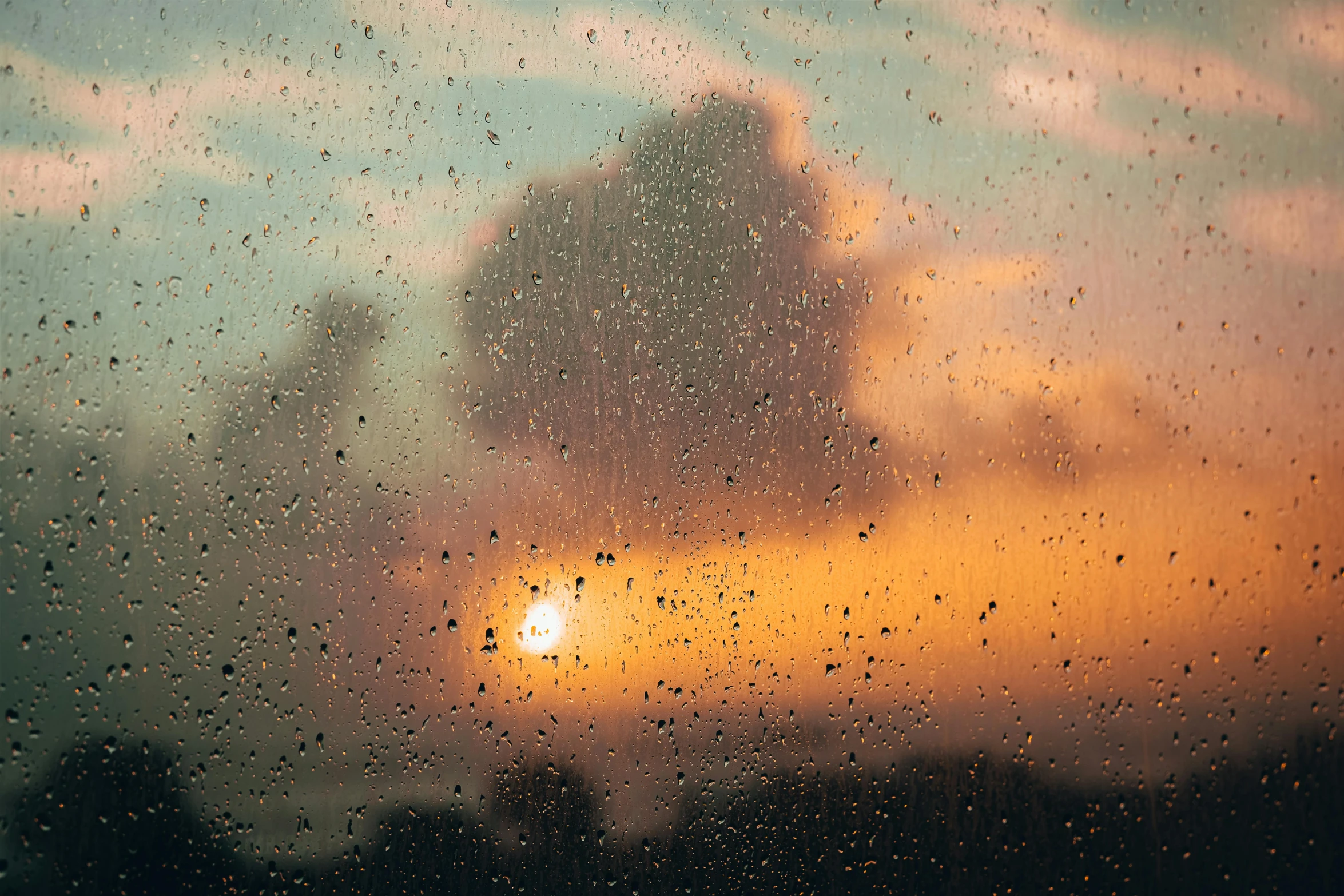 sunset seen through rain covered window on cloudy day