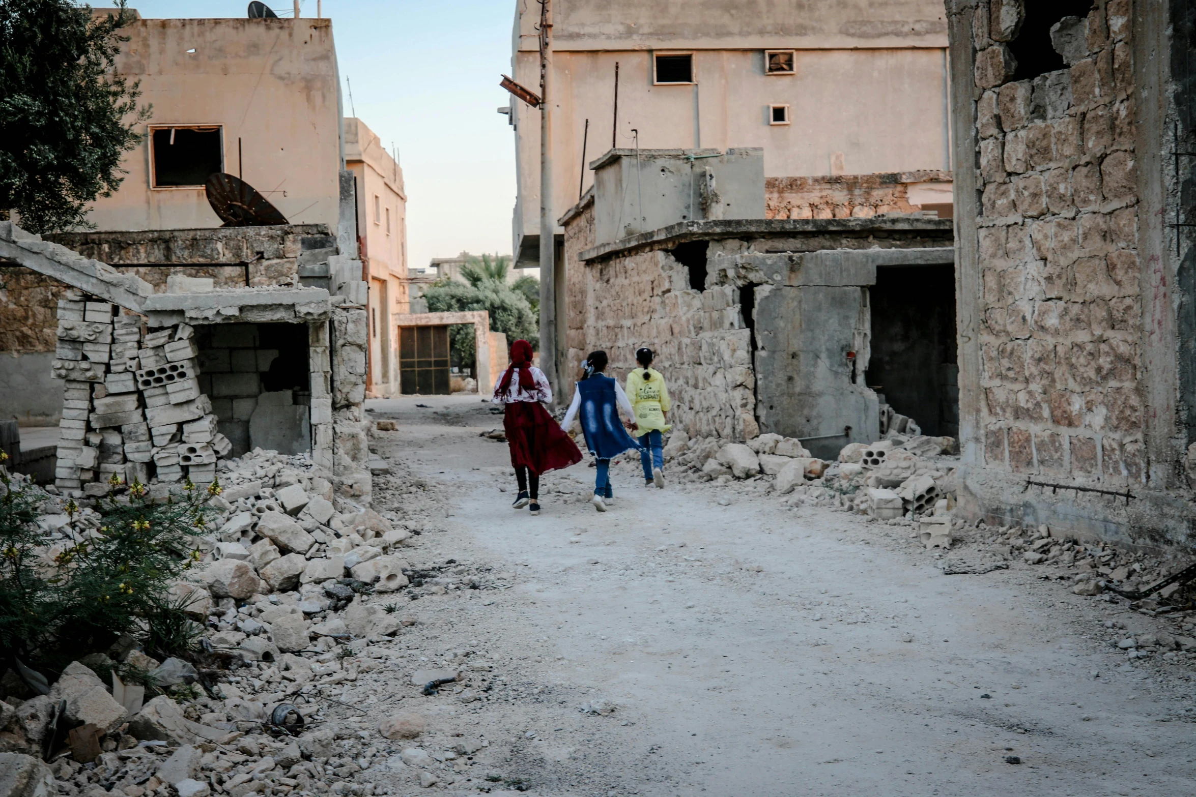 three people walk down an old and run down road