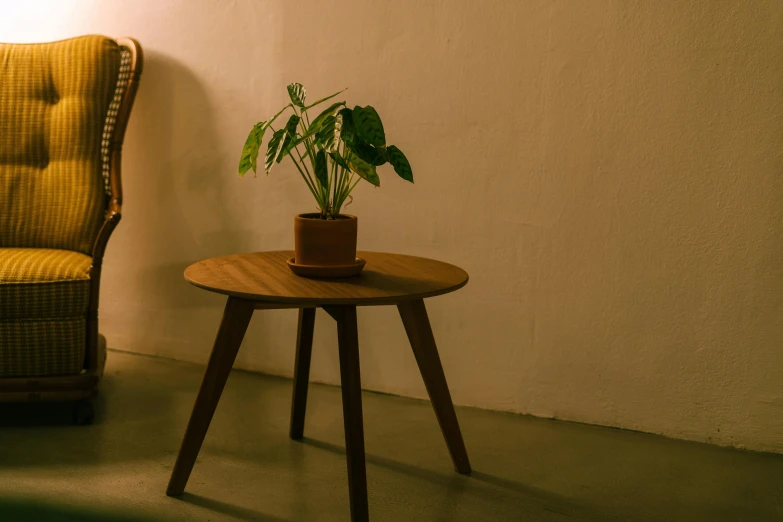 a wooden table next to a yellow chair with a plant on top of it