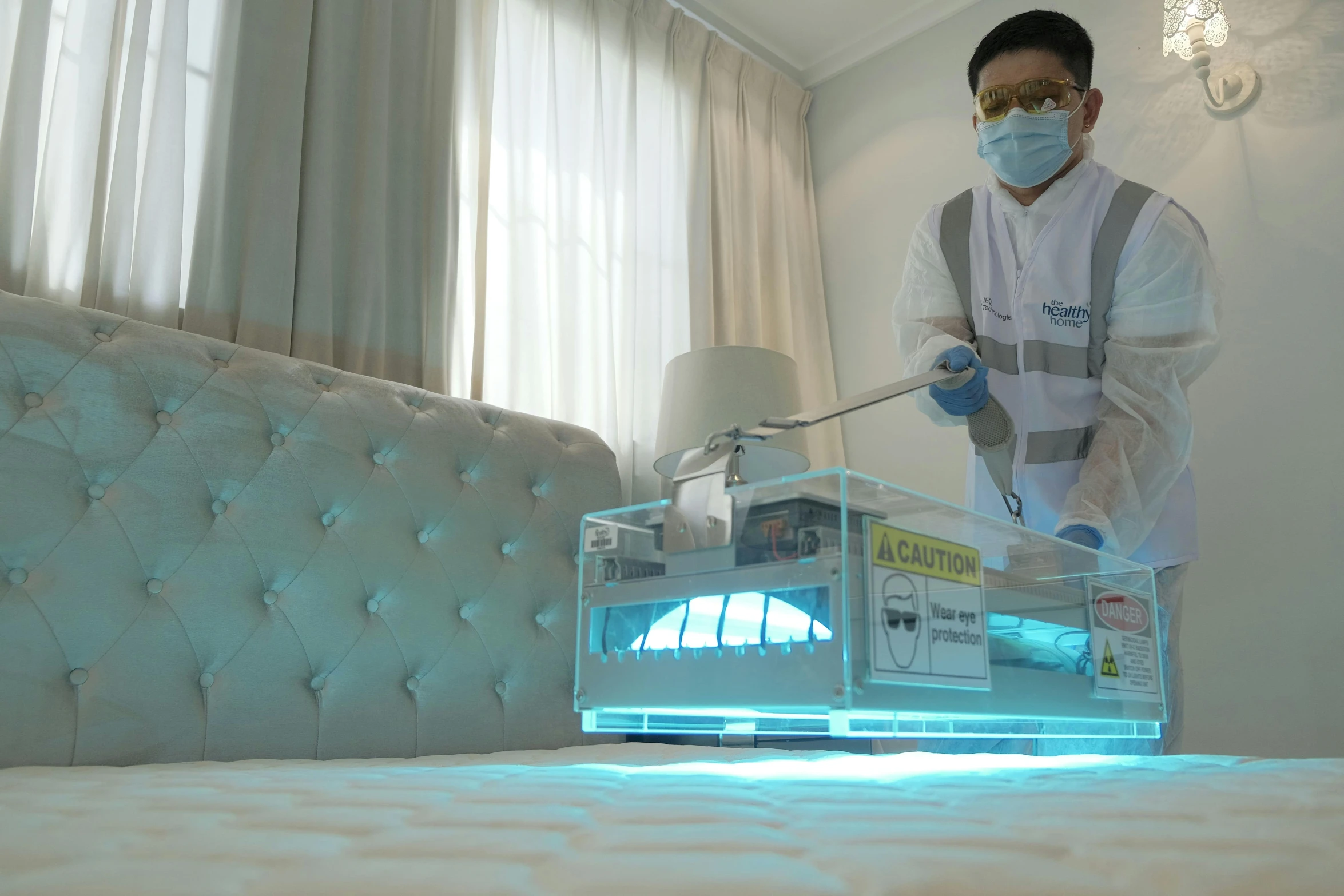 a person with gloves and a mask is fixing a bed in front of a tv screen