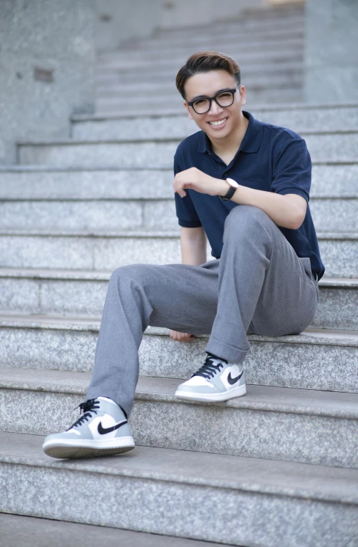 a man with glasses sitting on steps in front of a staircase