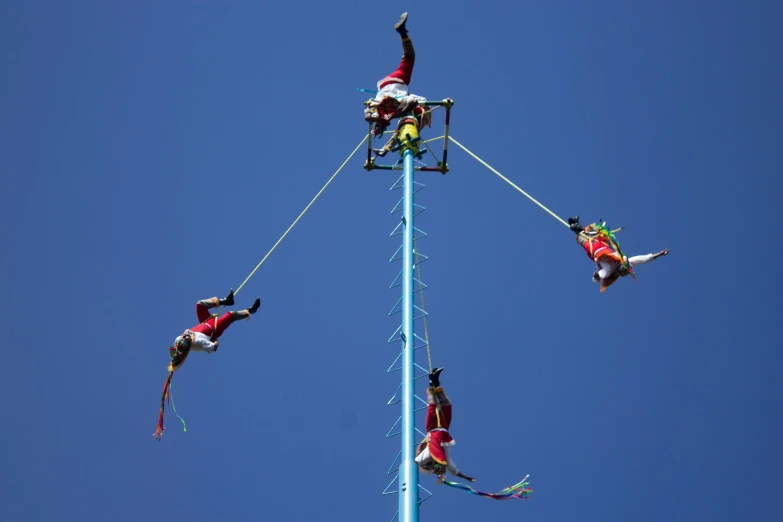 a group of people in colorful clothing on skis doing tricks on a tall pole