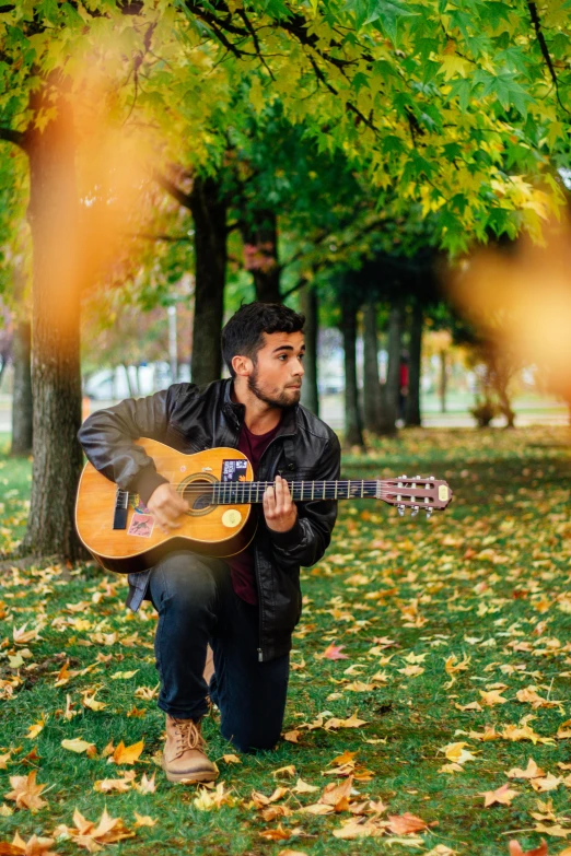 a man sitting on the ground playing an acoustic guitar