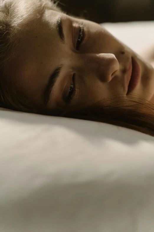 a woman with long hair sleeping on a white bed