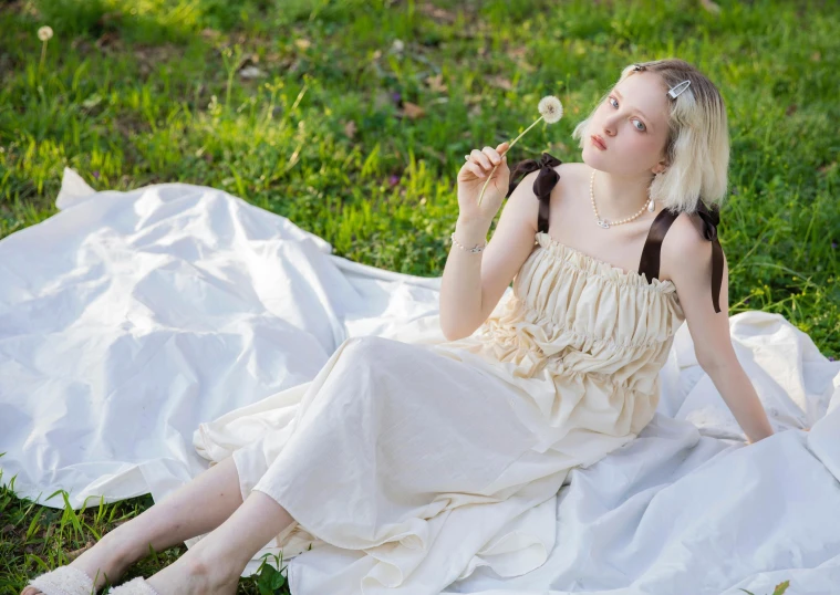 a woman in a white dress is sitting on a white blanket