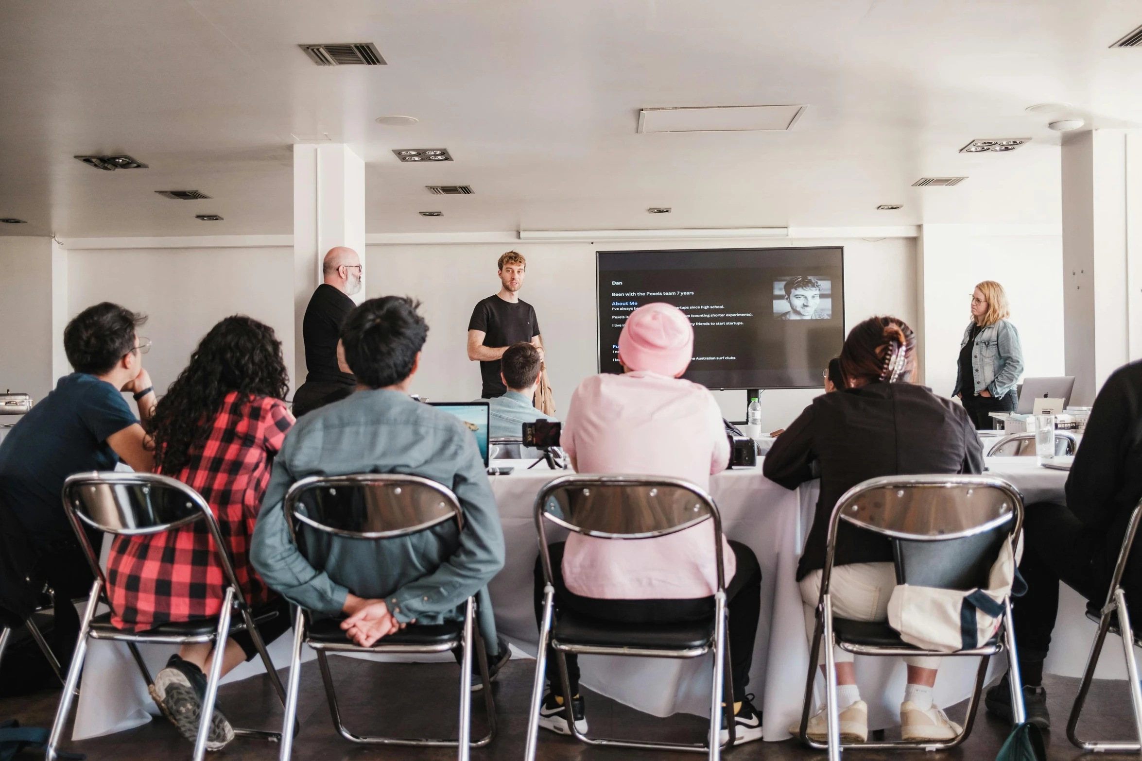 several people seated and facing a projector screen on a wall