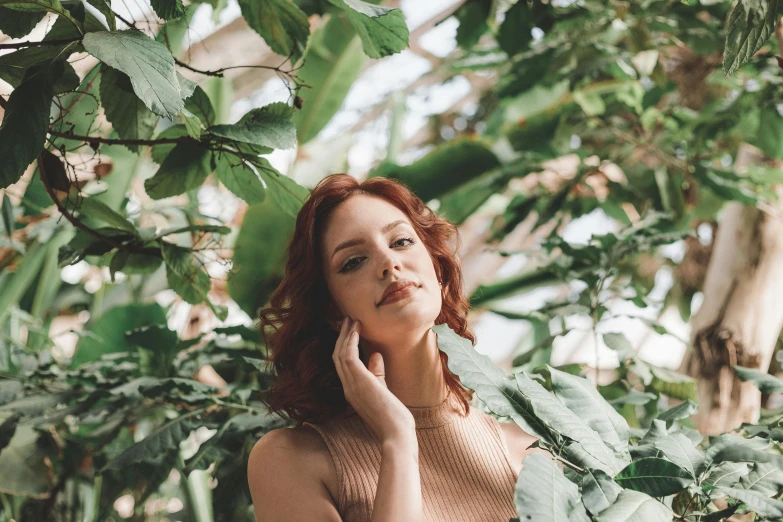 a woman is posing near a plant and posing for the camera